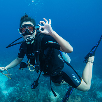 girl making ok sign while scuba diving at ray caye